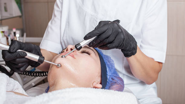 Aesthetician performing a microdermabrasion treatment on a female client in a spa setting.